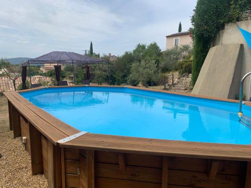 une grande piscine bleue avec une terrasse en bois dans l'établissement Maison d'hôtes les Jardinettes en Luberon, à Villelaure
