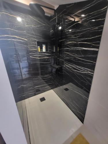 La salle de bains est pourvue d'une douche avec du carrelage noir. dans l'établissement maison indépendante avec piscine, à Saint-Médard-en-Jalles