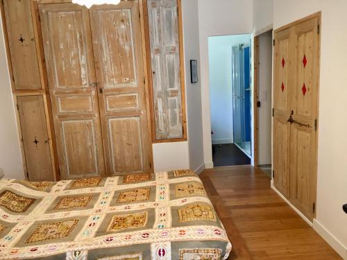 a bedroom with a bed and wooden floors and doors at Chambre indépendante avec coin cuisine in La Cadiere d'Azur