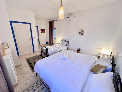 a bedroom with a large white bed and a room with two beds at Dar Bakkali Nadi in Tangier