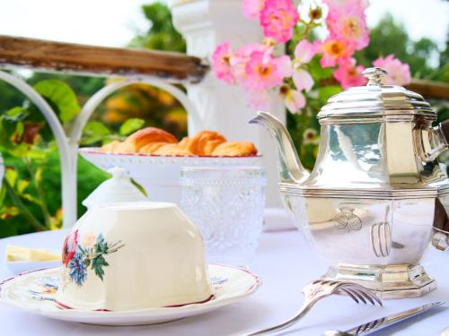 a table with a tea kettle and a basket of croissants at Domaine du cloitre in Pléneuf-Val-André