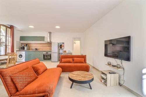 - un salon avec un canapé orange et une télévision dans l'établissement Appart de 70m2 en RDC à 6 mn à pied des monuments, à Nîmes