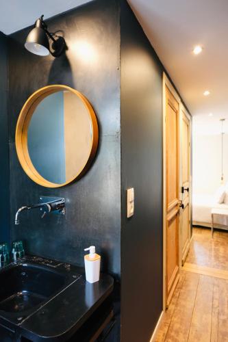 une salle de bain avec un lavabo et un miroir au mur dans l'établissement Nuit en Ville Pompidou Lille La Madeleine, à La Madeleine