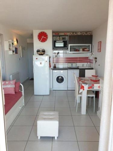 Il comprend une petite cuisine avec une table et un réfrigérateur blanc. dans l'établissement SAVANNA BEACH I Joli T2 vue mer piscine Cap d'Agde, au Cap d'Agde