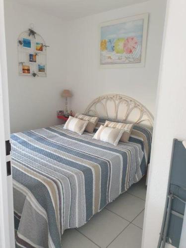 - un lit avec une couverture rayée dans une chambre dans l'établissement SAVANNA BEACH I Joli T2 vue mer piscine Cap d'Agde, au Cap d'Agde