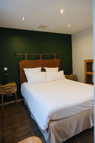 - une chambre avec un grand lit blanc et un mur vert dans l'établissement Nuit en Ville Pompidou Lille La Madeleine, à La Madeleine