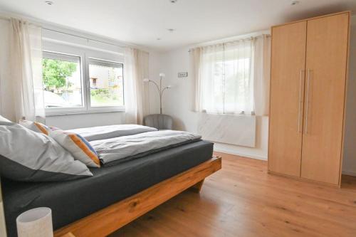 a bedroom with a bed and two windows at Entspannung und Erholung, Ferienwohnung mit traumhaftem Blick in die Natur in Oberaurach