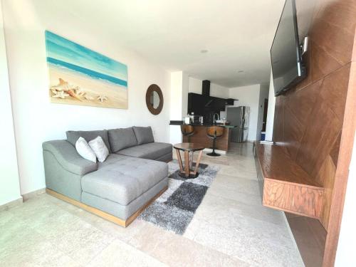 a living room with a couch and a flat screen tv at Vista al mar en Bucerías in Bucerías