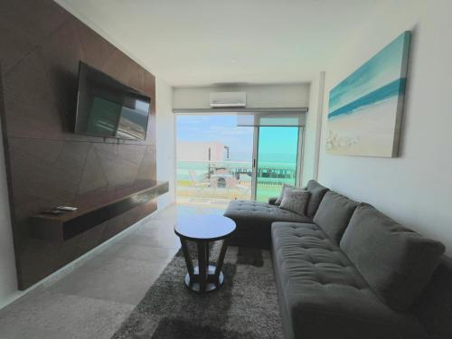 a living room with a couch and a tv and a table at Vista al mar en Bucerías in Bucerías