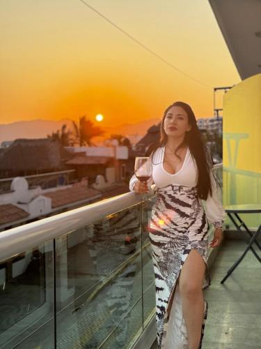 a woman standing on a balcony with a glass of wine at Vista al mar en Bucerías in Bucerías