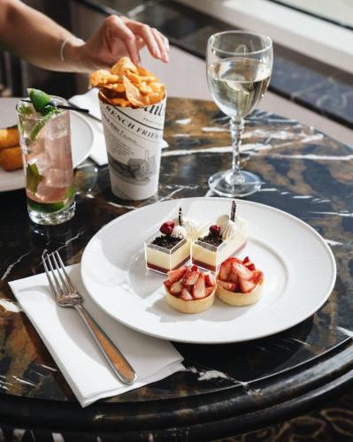 a plate of desserts on a table with a glass of wine at The Venetian Resort Las Vegas By Suiteness in Las Vegas