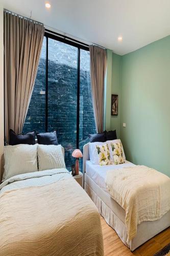 2 Betten in einem Schlafzimmer mit einem großen Fenster in der Unterkunft Live With Passion Pool Villa in Pak Chong