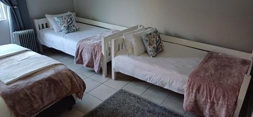 a room with two twin beds and a rug at Winemaker's Rest- Two Bedroom House in Oudtshoorn