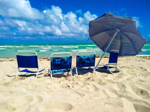 three chairs and an umbrella on a beach at Castle 1120 Bayview Studio, Beach access, Pool, Tennis, Free parking in Miami Beach