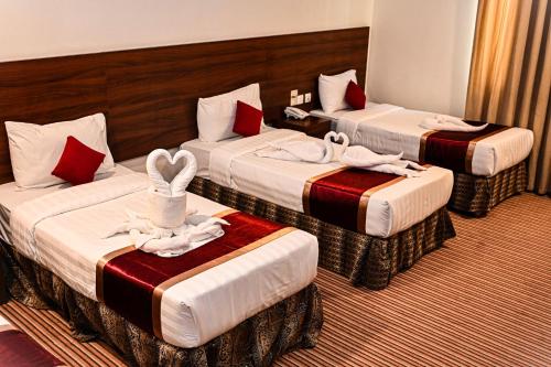 a hotel room with three beds with towels on them at فندق أبراج المسك Abraj Almisk Hotel in Makkah