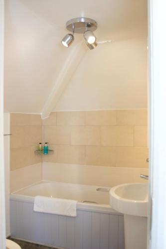 a bathroom with a bath tub and a sink at Durdle Door Hotel in Lulworth Cove