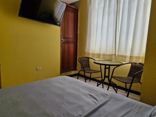 a room with a bed and a table and chairs at Hospedaje El Edén in Víctor Larco Herrera