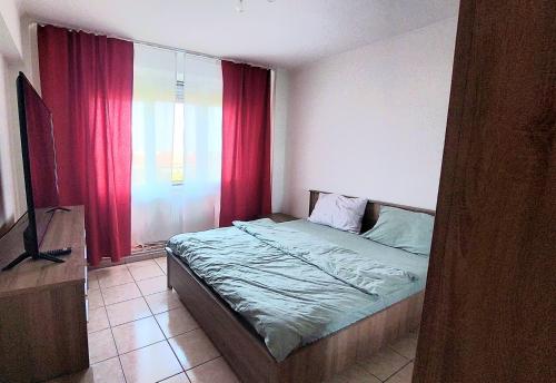 a bedroom with a bed and a window with red curtains at Arad central apartment in Arad