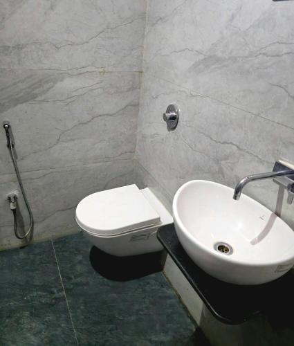 a bathroom with a white toilet and a sink at Parmeshwar Lodge in Tuljapur