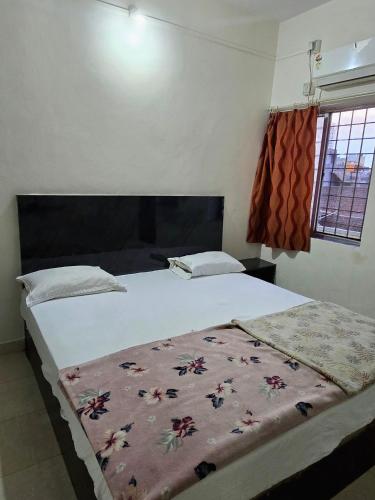 a bedroom with a large bed with a blanket on it at Parmeshwar Lodge in Tuljapur