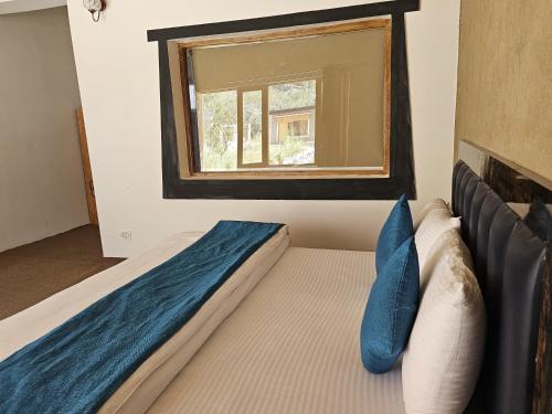 a bedroom with a bed with blue pillows and a window at HUNDER TAMARIX RESORT in Leh