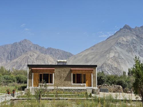 a small house with mountains in the background at HUNDER TAMARIX RESORT in Leh