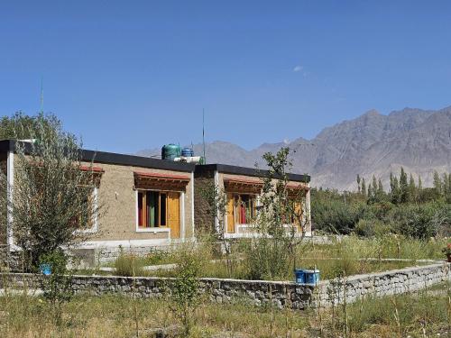 a house in a field with mountains in the background at HUNDER TAMARIX RESORT in Leh