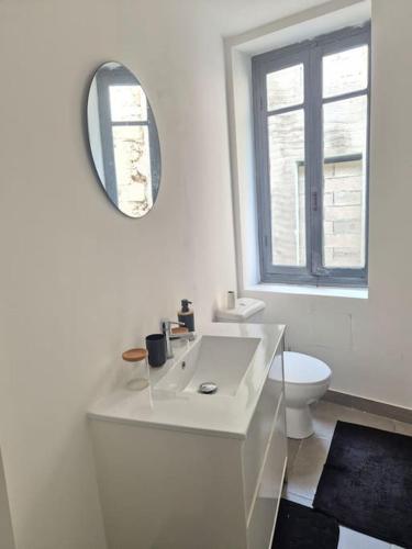 La salle de bains blanche est pourvue de toilettes et d'un miroir. dans l'établissement charmante maison de ville, à Narbonne