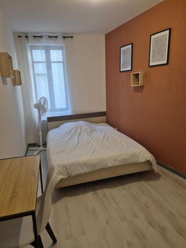 une chambre avec un lit, une table et une fenêtre dans l'établissement charmante maison de ville, à Narbonne