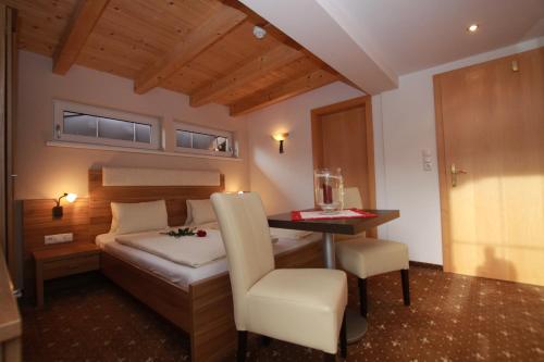 a bedroom with a bed and a desk with a chair at Pension Edelweiss in Breitenbach am Inn