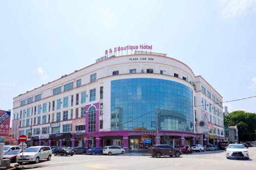 a large building on a city street with cars parked at B&S Boutique Hotel in Batu Pahat