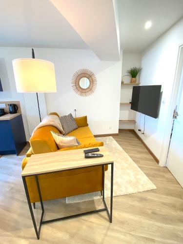 un salon avec un canapé jaune et une table dans l'établissement L'Essentiel - Cocon lumineux au cœur de Hauteville, à Hauteville-Lompnes