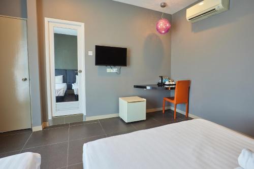 a bedroom with a bed and a desk and a tv at B&S Boutique Hotel in Batu Pahat