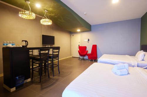 a hotel room with two beds and a bar with red chairs at B&S Boutique Hotel in Batu Pahat