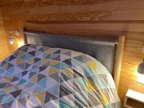 a bed with a colorful comforter in a room at L'écolodge de Laeti in Lunéville