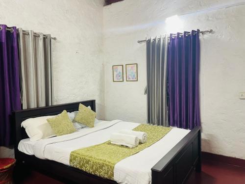 a bedroom with a large bed with purple curtains at Thottom Stays Private Bungalow in Munnar