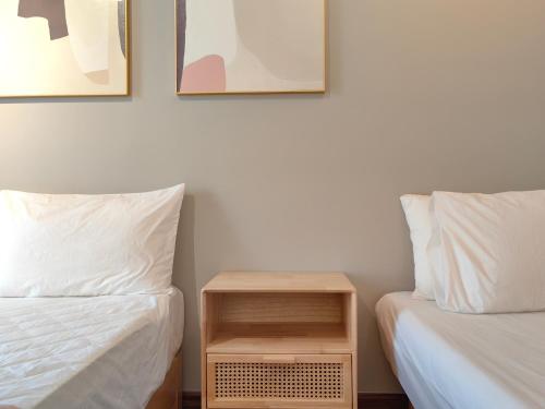two beds with white sheets and a nightstand between them at K Avenue Modern Style Studio (5 Mins to Airport) in Kota Kinabalu