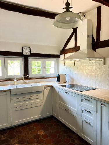 une cuisine avec des placards blancs et une horloge murale dans l'établissement Maison de campagne rénovée - 15 personnes - 1h30 de Paris - Piscine Pétanque Étang, à Noyers