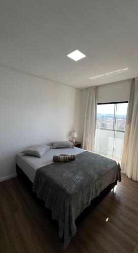 a bedroom with a large bed with a large window at Apartamento Modernizado in Joinville