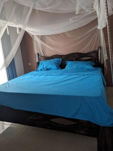 a bedroom with a blue bed with a canopy at Imena resort in Bugesera