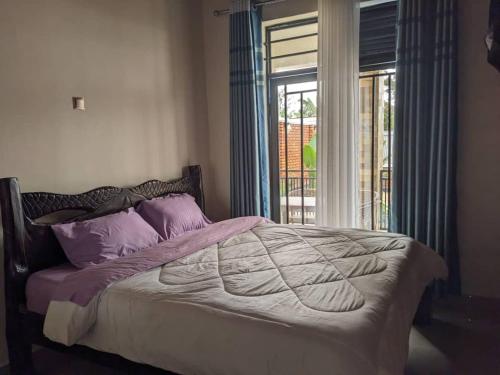a bedroom with a bed with purple pillows and a window at Imena resort in Bugesera