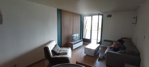 una mujer sentada en un sofá en una sala de estar en Ax 3 domaines, en Ax-les-Thermes