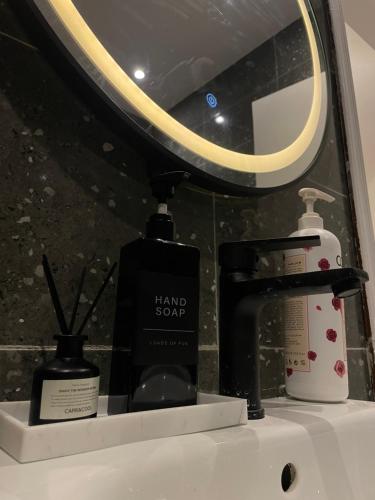 a bathroom counter with a sink with a mirror and a bottle of soap at Luxury apartment in Boulevard Hittin in Riyadh