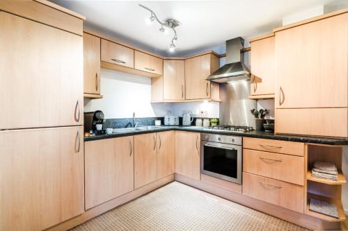 a kitchen with wooden cabinets and a stove top oven at 2BR Modern Flat With Free Parking - Private Garden in Heeley