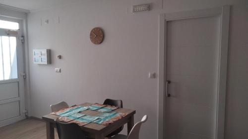 a dining room with a table and a clock on the wall at Pensión atlantico in Muxia