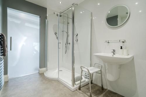 a white bathroom with a shower and a sink at The Roxburgh Guest Accommodation in Berwick-Upon-Tweed