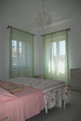 a bedroom with a bed and two windows with curtains at Domus Rosea in Marina Palmense