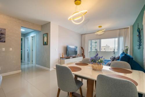 a dining room and living room with a table and chairs at Encantador Apartamento 100m da Praia com vista mar in Porto Belo