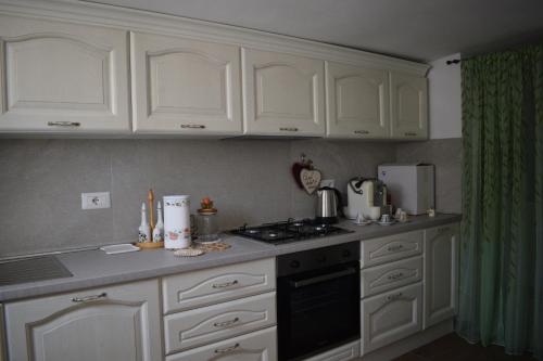 a kitchen with white cabinets and a stove top oven at Domus Rosea in Marina Palmense