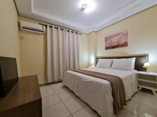 a hotel room with a bed and a television at Burle Marx Centro 4 quart, portaria 24h,área nobre in Montes Claros